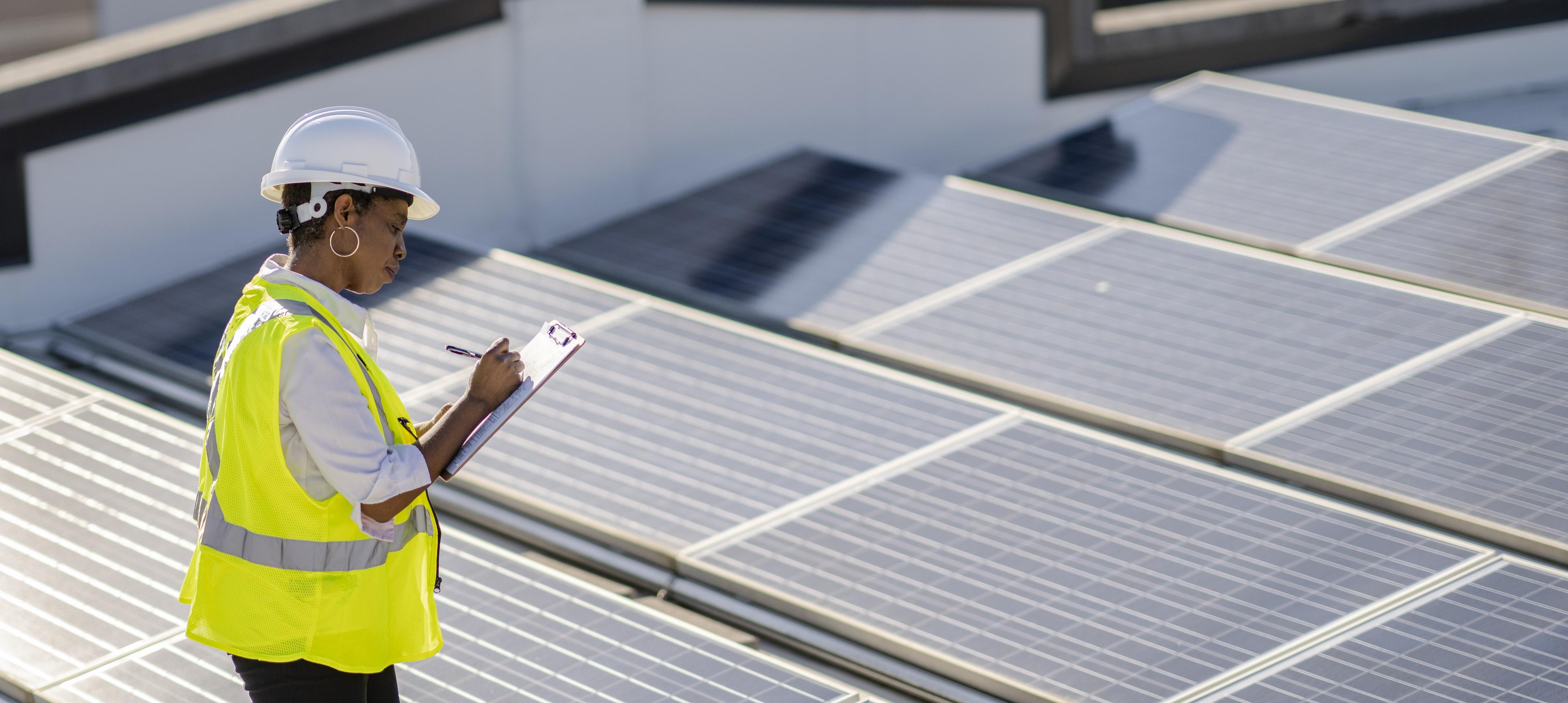 A woman monitors rooftop of solar panels to ensure efficiency and function.